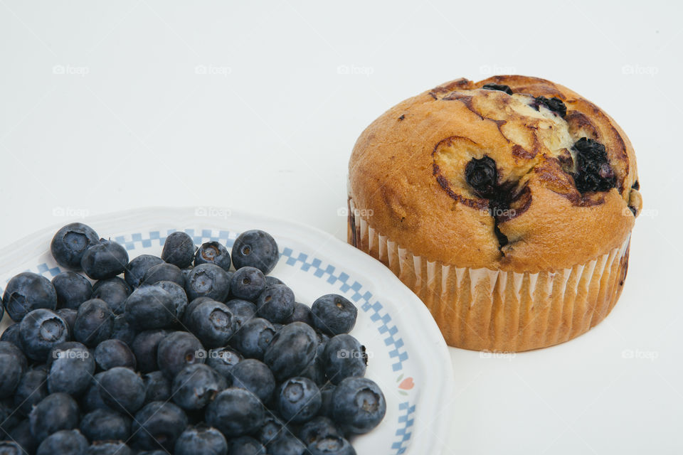 Blueberries in a bowl next to a blueberry muffin