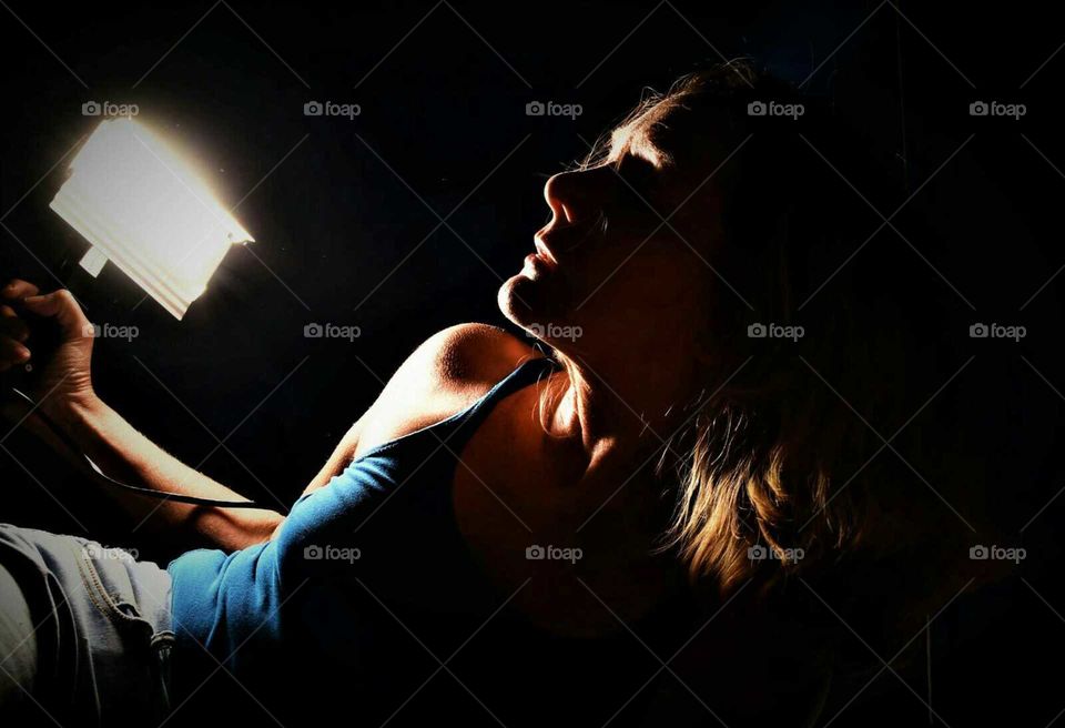 low key portrait of a woman holding a vintage flashlight