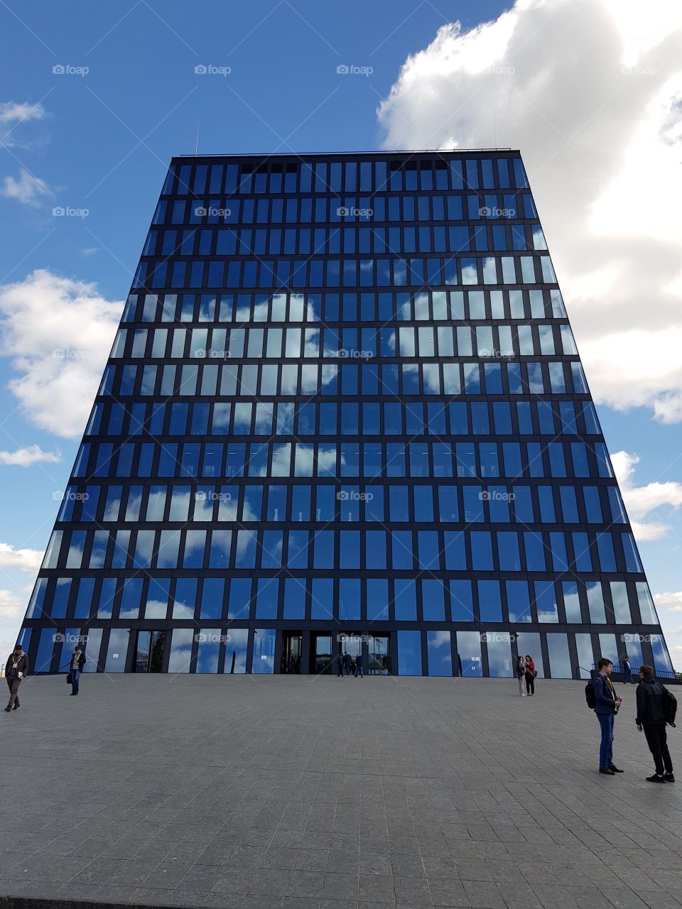 Modern building with glass facade reflects the sky with clouds