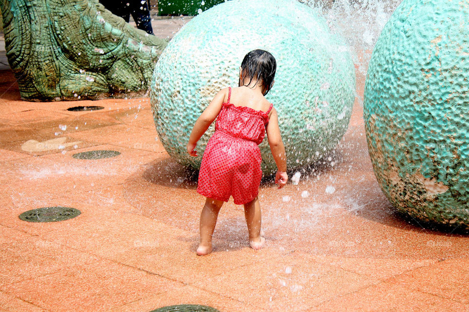 Little girl playing with water fountain at the park