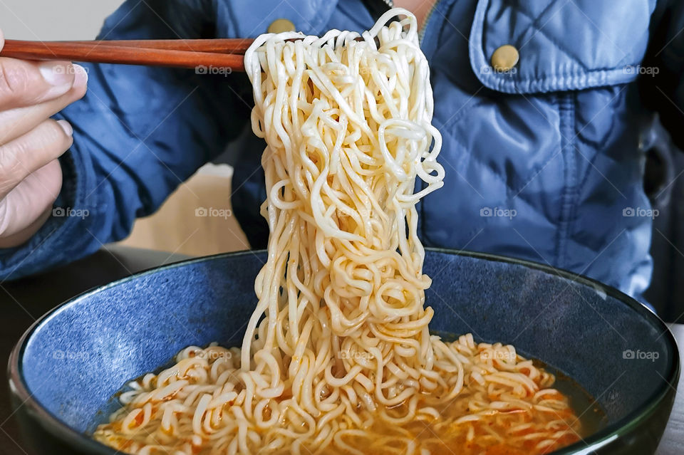 Instant noodles.  Fast and easy cooking food.  Selective focus.  Lady having noodles with chopsticks.