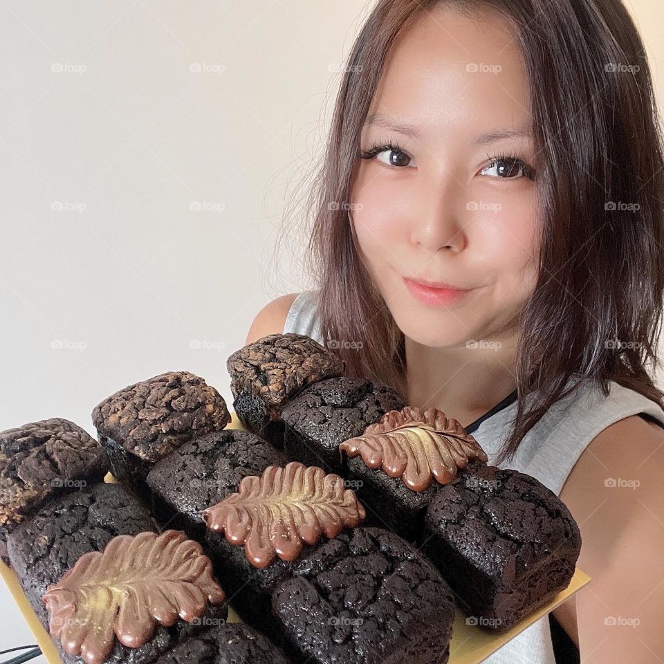 Asian lady with Dark homemade block brownies in different flavours  