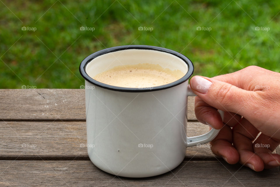 hand holding metal cup of coffee