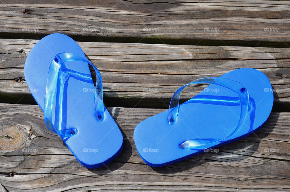 Blue flip flops on a boardwalk. 