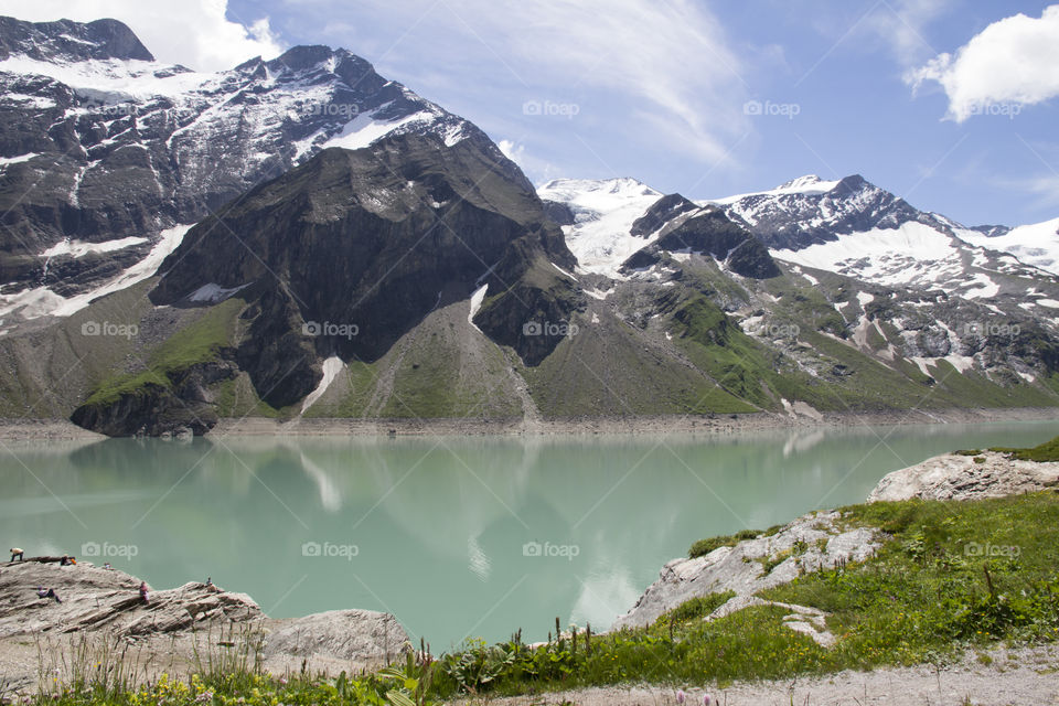 Hiking trail in the mountains, view of lake and mountain peaks with snow 