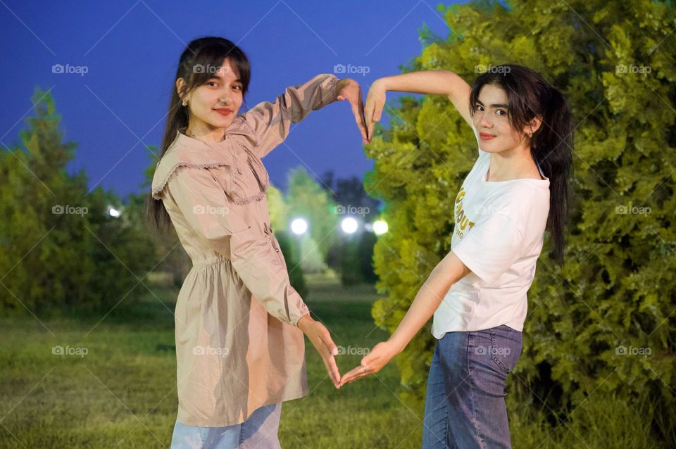 Sisters posing a heart for picture 