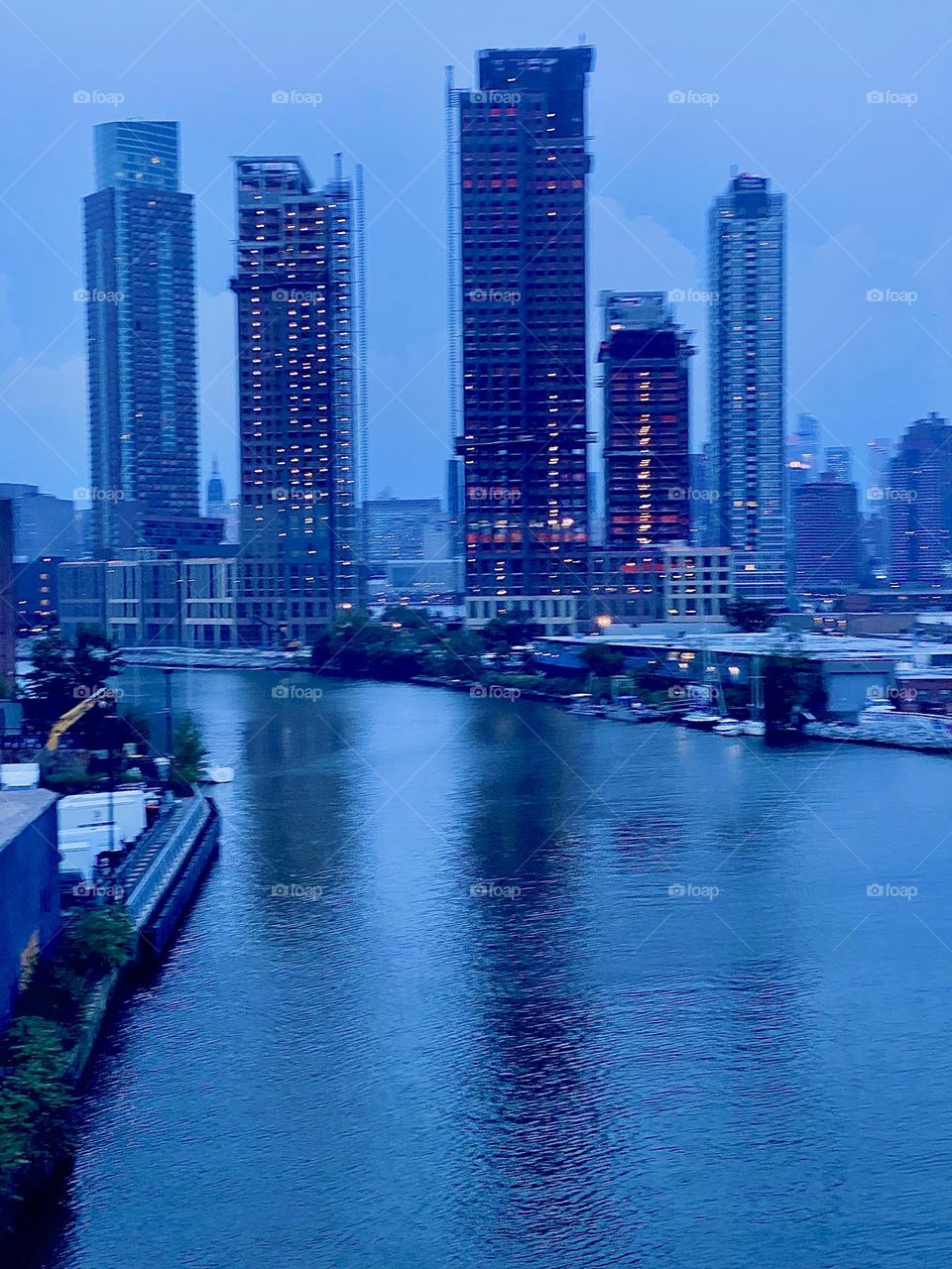 This is „Newtown Creek“ seen from the „Pulaski Bridge“ in LIC, Queens. The scaffolded nearby high rises are under construction. Behind them in the distance we can see „Manhattan“. 2023. Hypnotic Productions