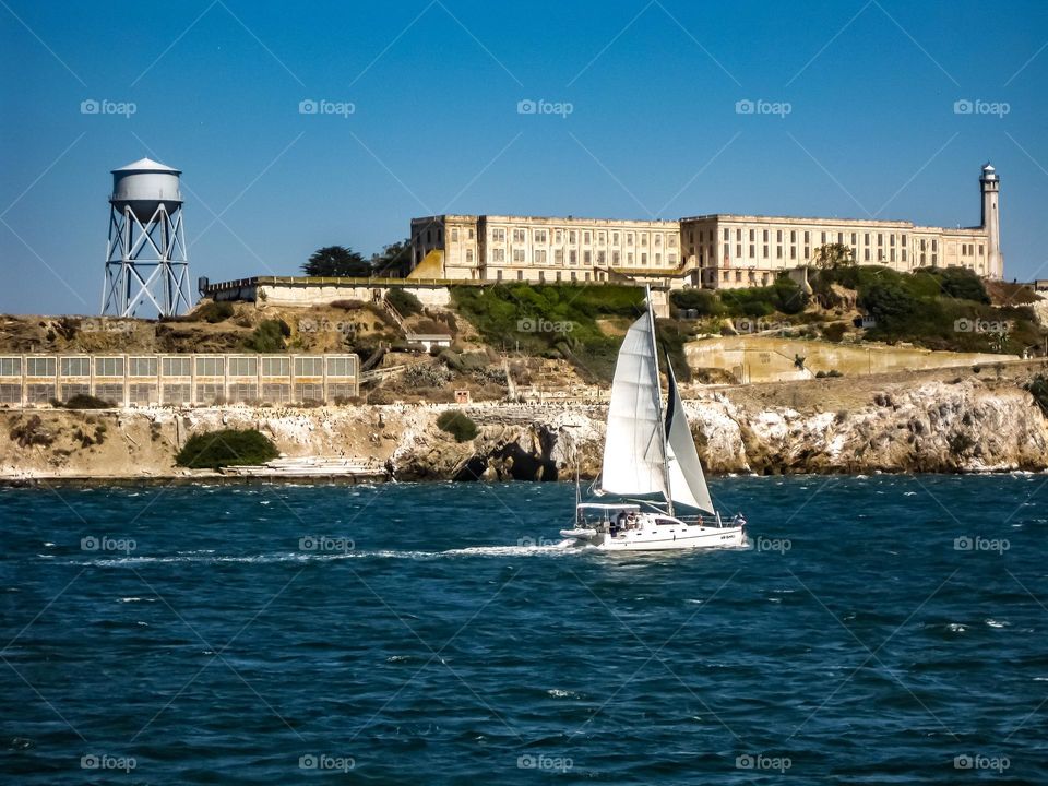 Sailboat sailing on a beautiful day on the San Francisco California bay with the former prison Alcatraz in the background 