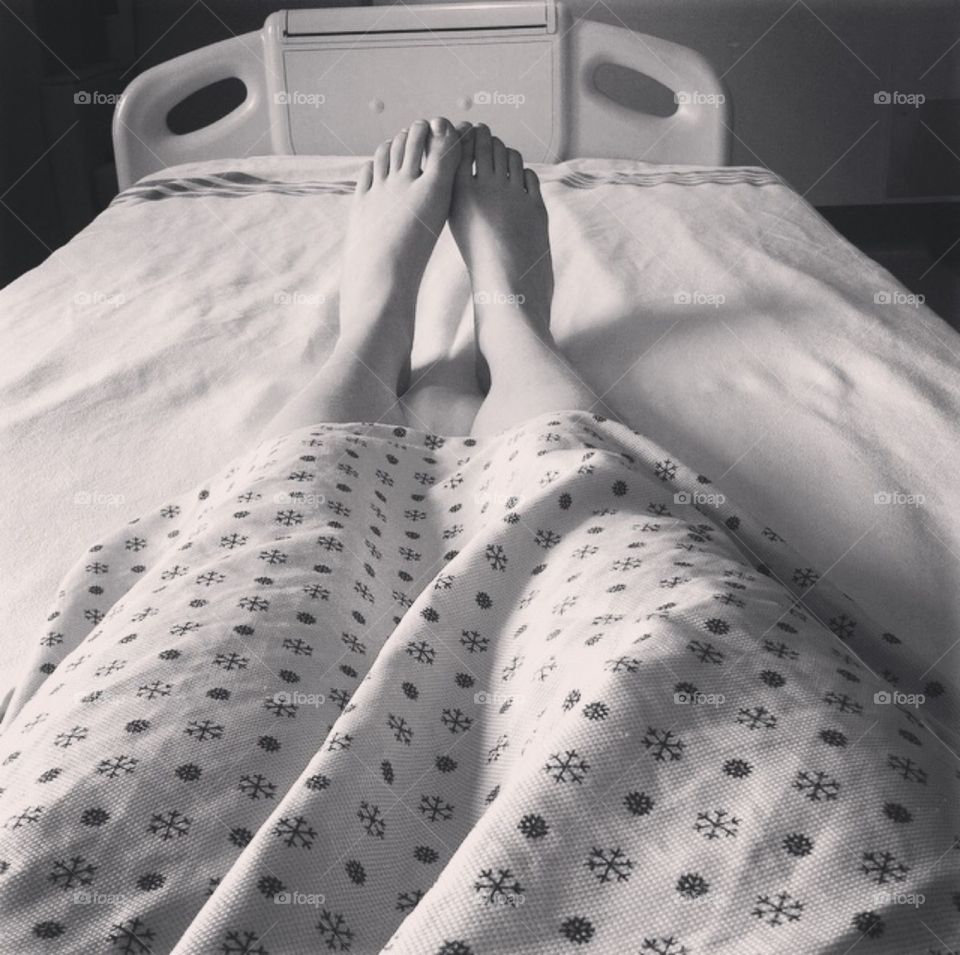 Have a little hope. Girl in hospital bed with shot of feet in hospital gown 