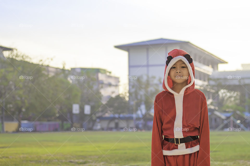 Asia boy wearing a red Christmas Background on the school lawn.