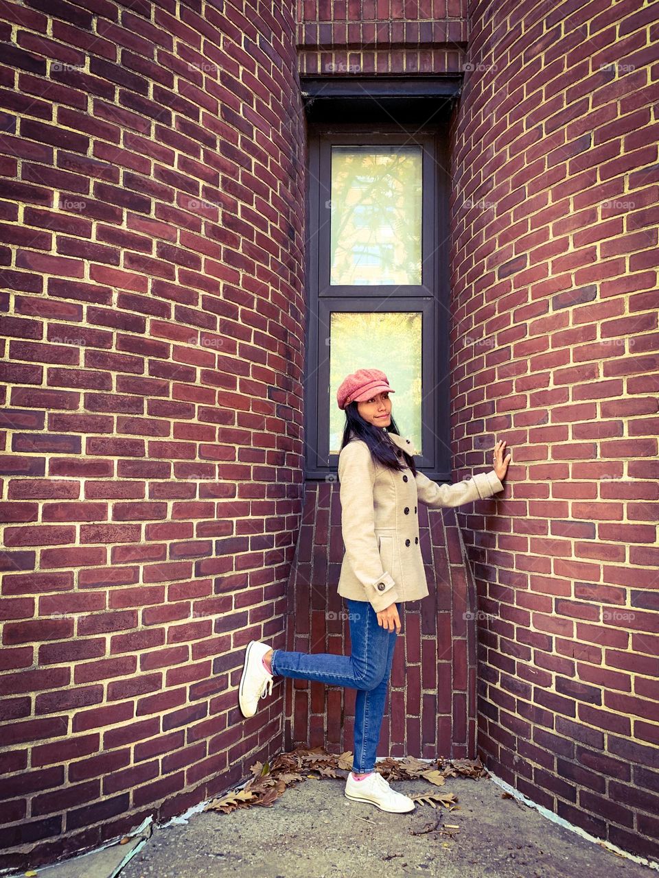 A woman standing against the bricks wall 