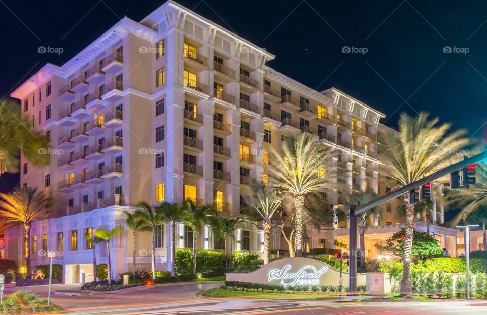 beach front residence building with colorful  accent lights and street lights glowing bright against a dark blue night sky