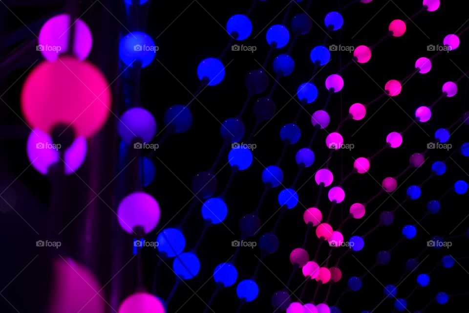 Christmas illumination shows us purple, blue and pink toned coloured against black background.