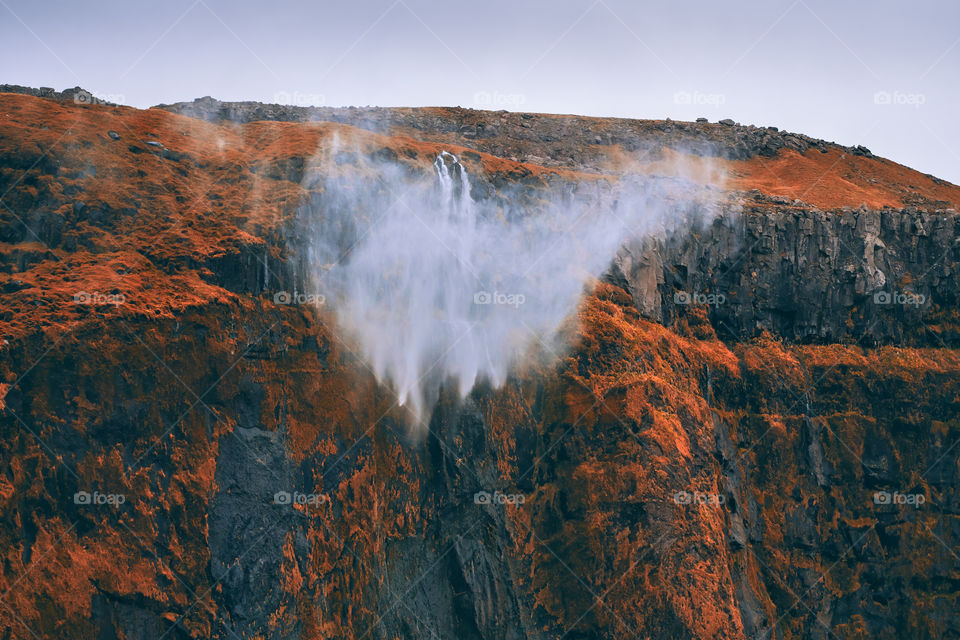 Dramatic scene of water from waterfall being blown away by strong and gusty storm winds off the steep cliff located in nearby Seljalandsfoss in Southern Iceland. Here photographed in early October 2019.