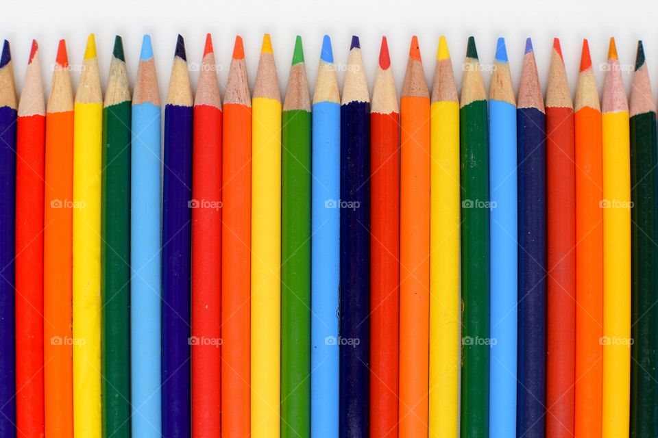 Arrangement of colored pencils over white background