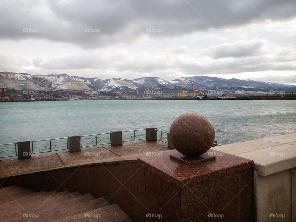 Descent to the sea. Embankment in Novorossiysk. Russia. View of a snow-covered mountain range. January.