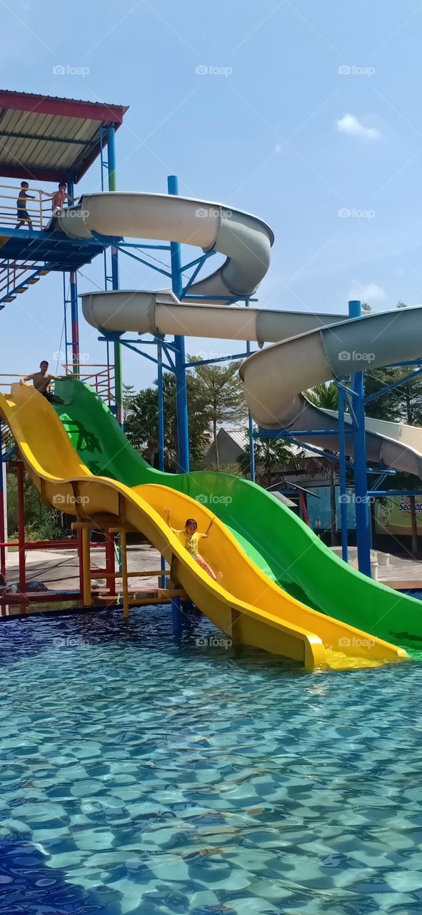 so excited with water slide in the pool. having fun with others.