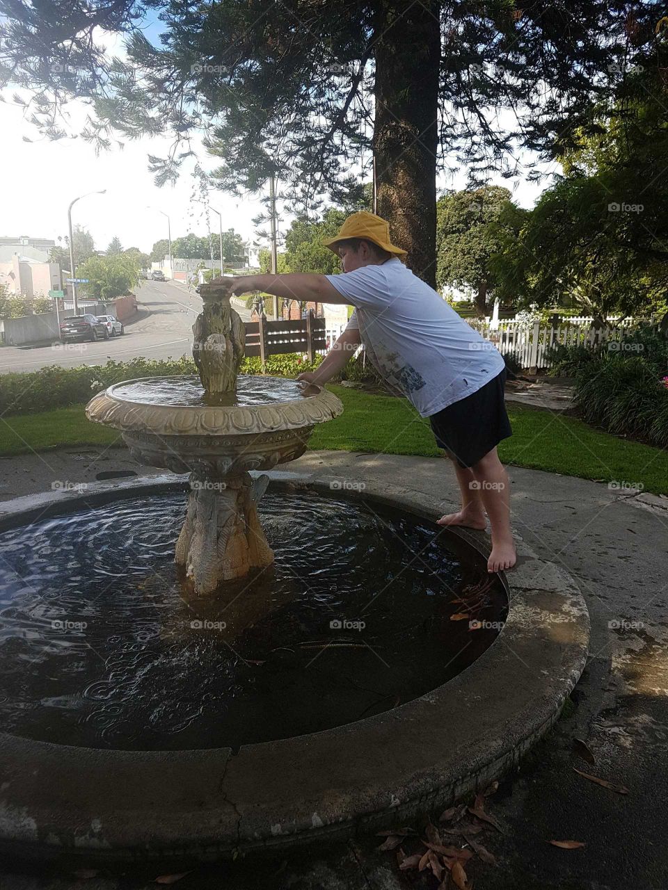 Water fountains are so much fun. Playful at the botanical gardens on a lovely day we went rock hunting my son is placing a rock in the water.
