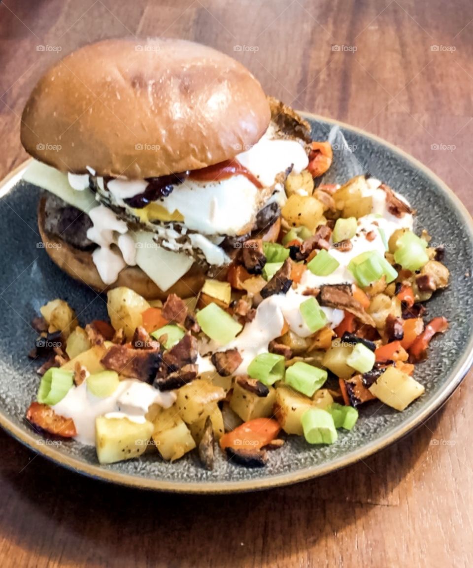 Tasty breakfast burgers complete with a sunny side up egg and bacon. With a side of potato and pepper hash. 