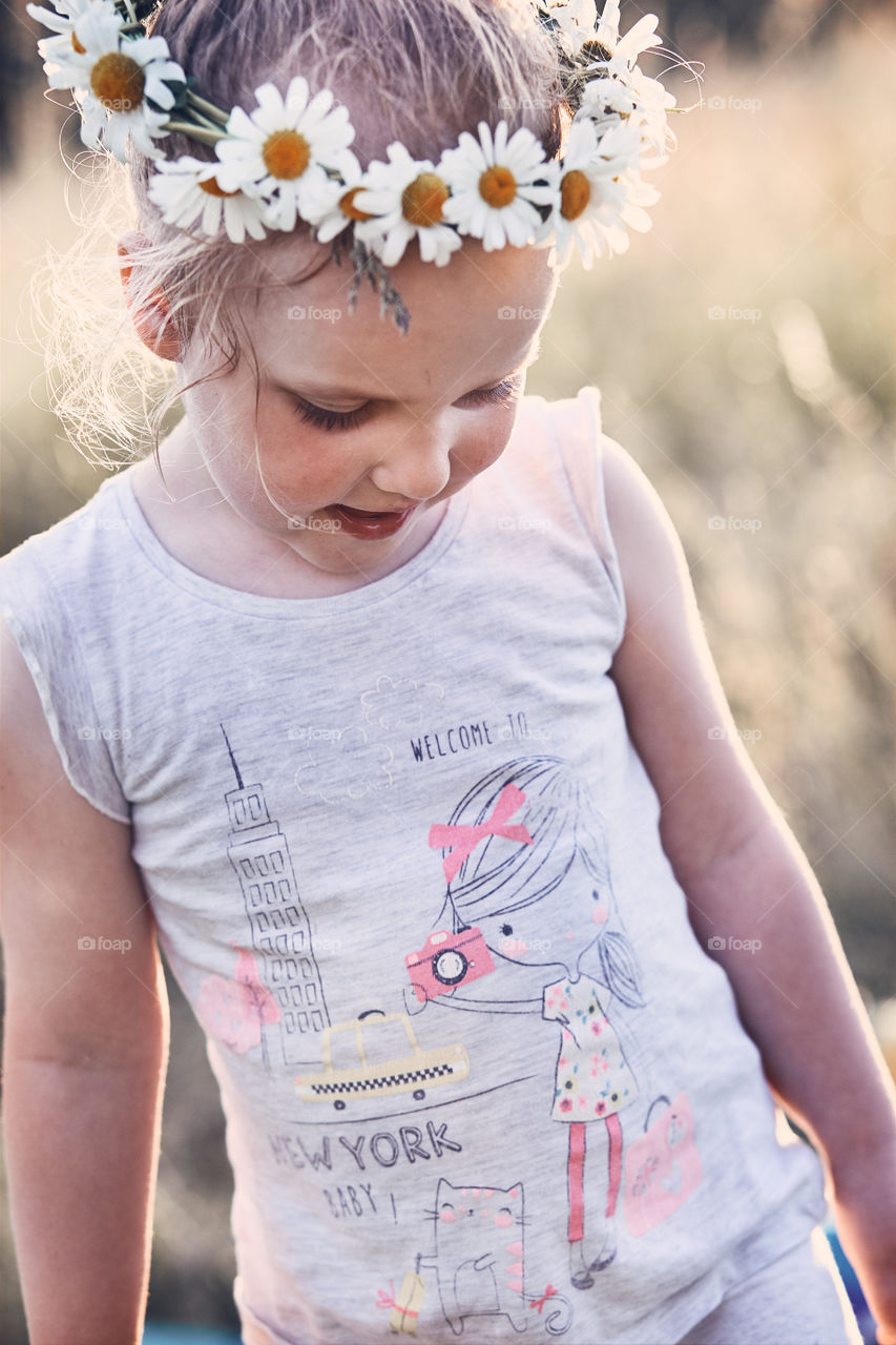 Little girl wearing a coronet of wild flowers on her head. Candid people, real moments, authentic situations