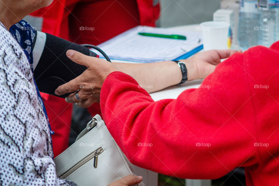 the doctor checks the blood pressure on the old woman