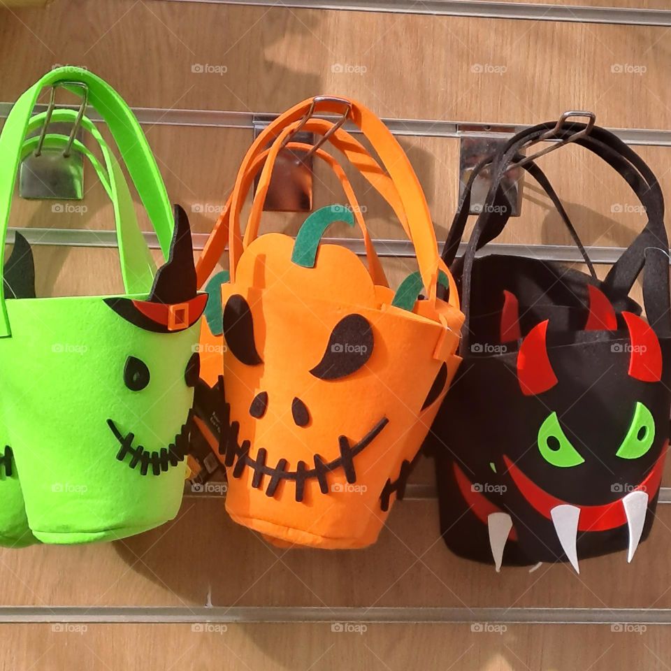 Kids trick or treat buckets for sale hanging in a shop. Scary  monster characters, bright colours