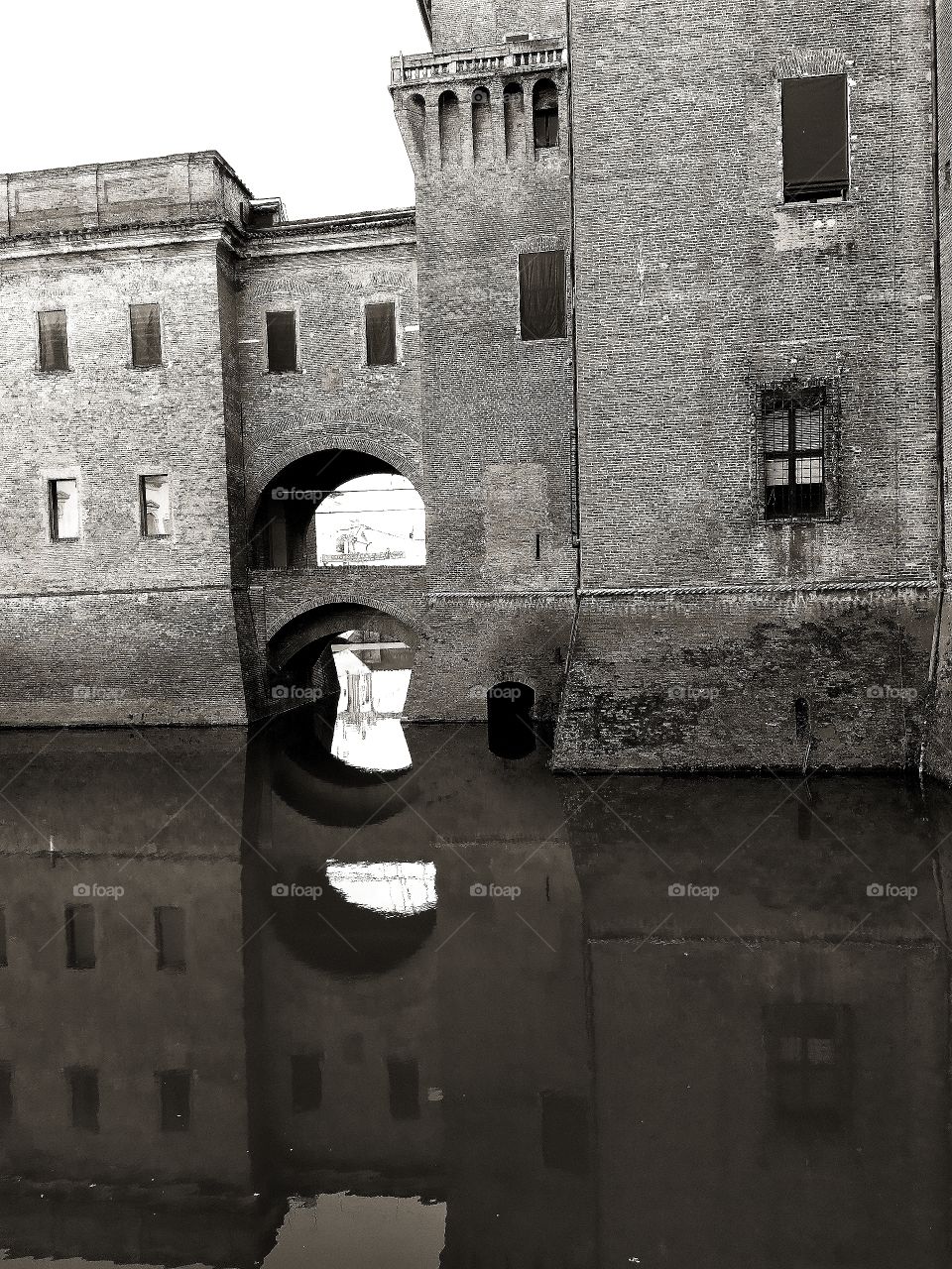 Reflection in the water of one of the towers of the Castello Estense castle