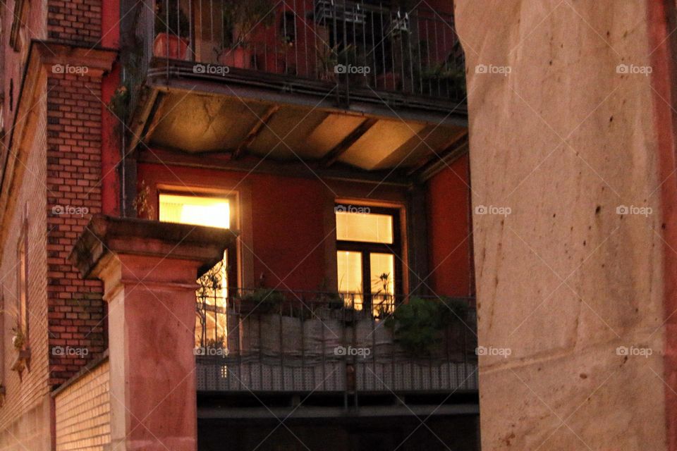 Warm golden light shines from two windows and illuminates the brick building in the evening