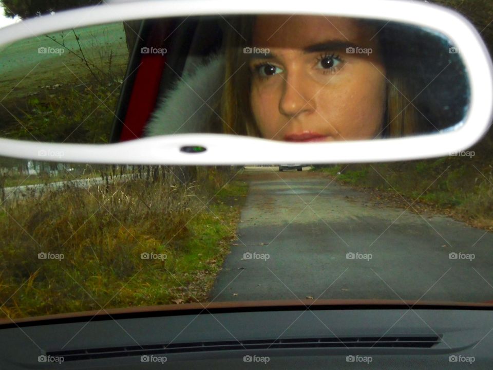 Woman face in the car mirror while driving