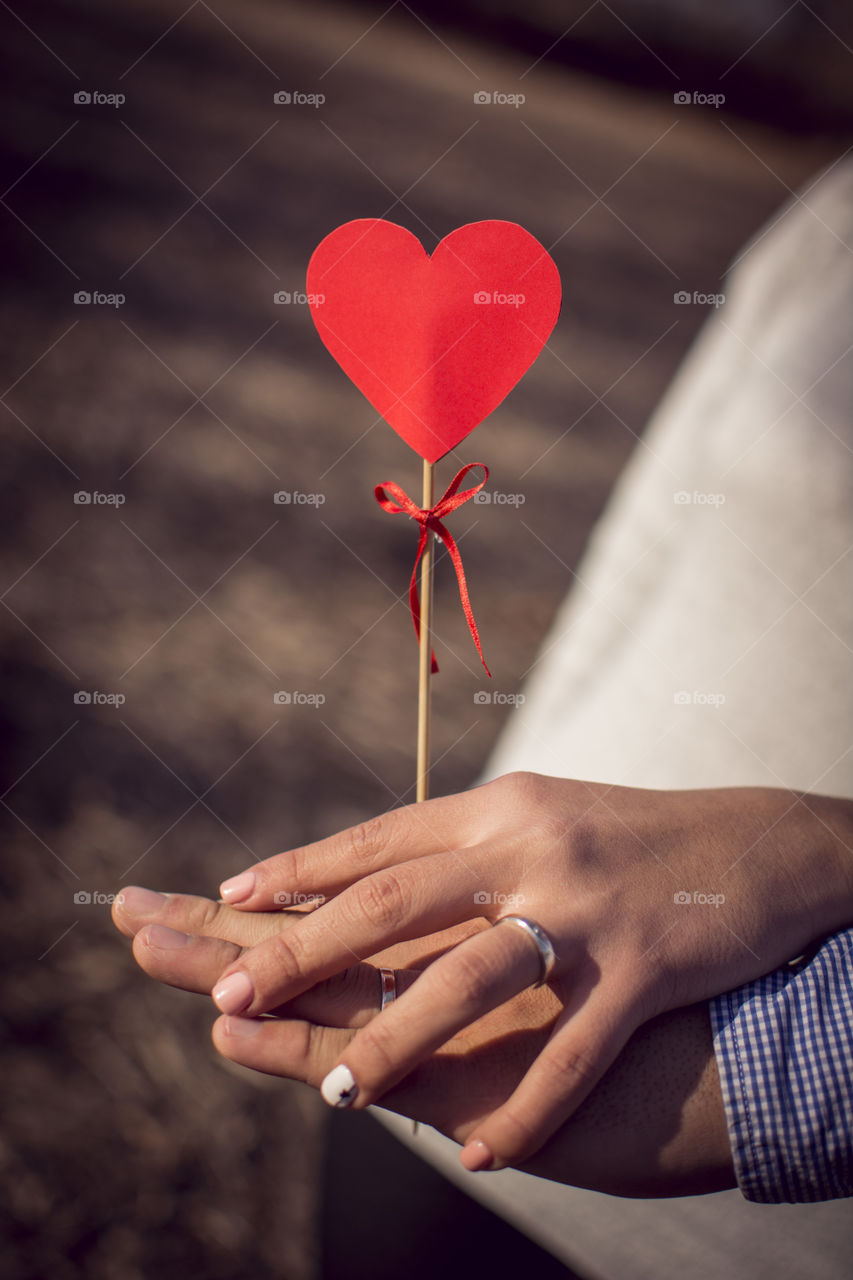 Hands holding a heart of paper symbolizing love in the couple