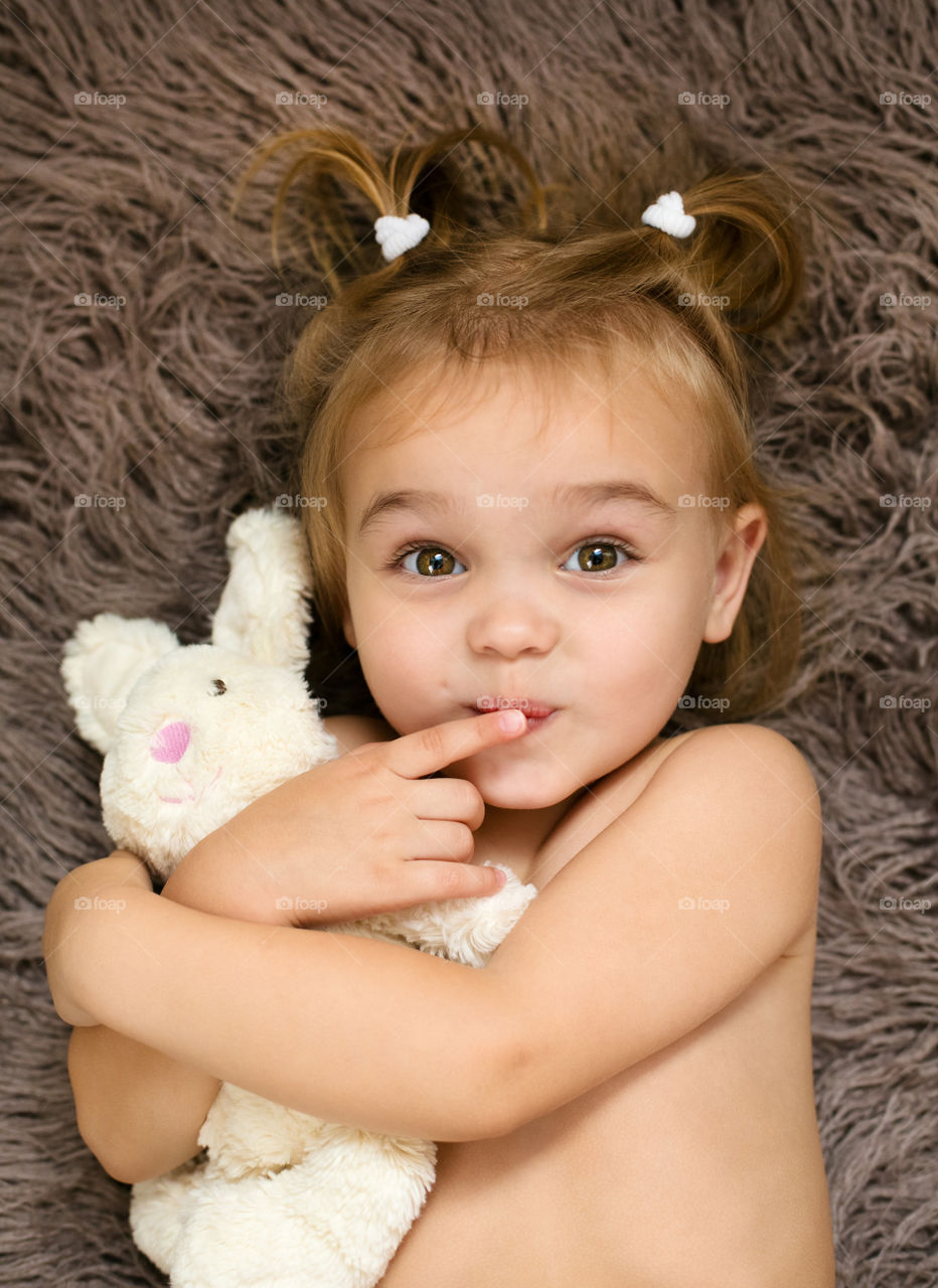 A little girl lying on rug with teddy bear