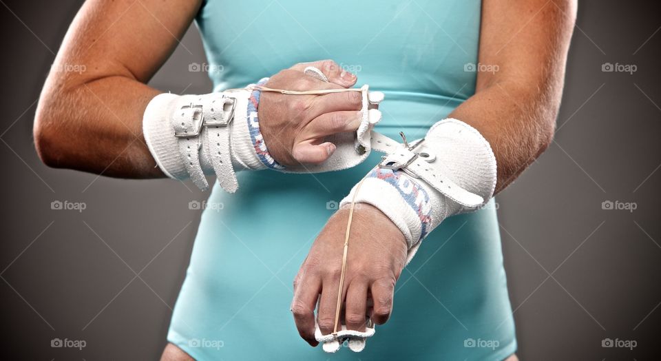 Gymnast getting ready for her uneven bars event by putting on her grips. 