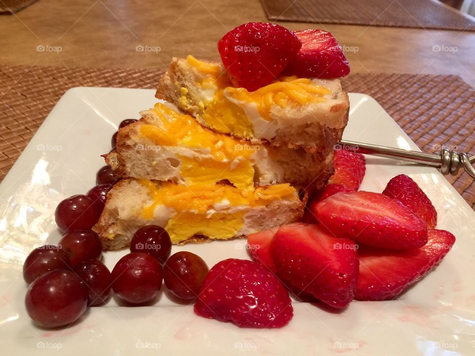 Sunny side Eggs on a multigrain bread with Cheddar cheese & enjoyed with fresh strawberries & grapes 