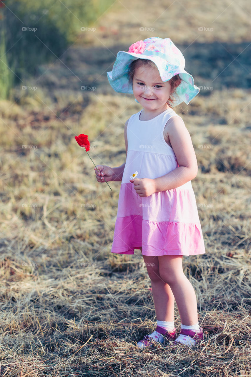 Lovely little girl in the field of wild flowers. Cute girl picking the spring flowers for her mom for Mother's Day in the meadow. Spending time close to nature