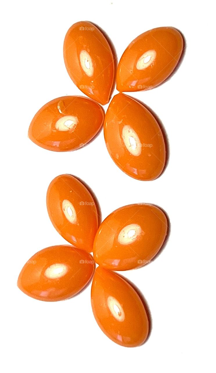 Orange granules of wax for depilation on white background.