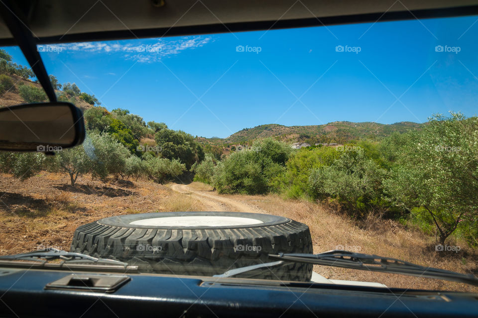 View from driver seat in 4x4 vehicle while driving through remote countryside.