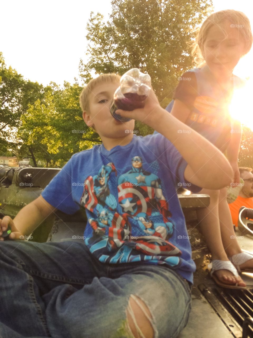 My son and a little friend drinking a soda in the sun.