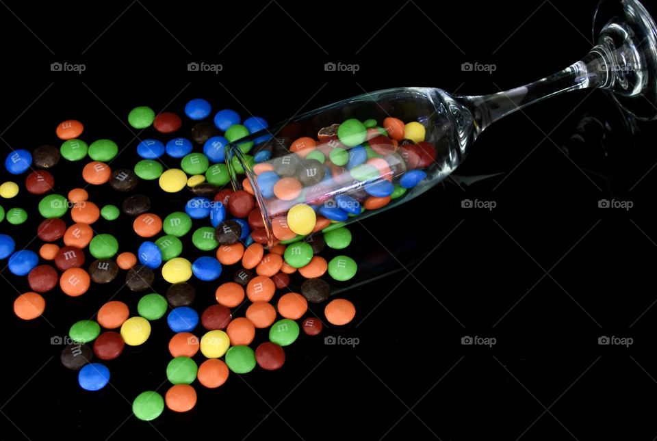 Colorful M&Ms spilling out of a glass 