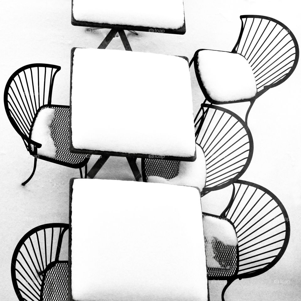 Black table and chairs covered with snow 