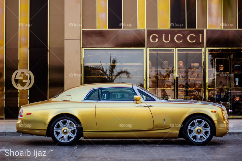 RollsRoyce Phantom Drophead Coupe infront of GUCCI. 
Gold theme.