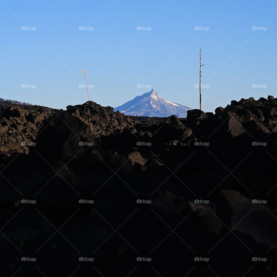 Morning sunrise on Mt. Jefferson in Oregon’s Cascade Mountain Range with a field of lava rock on a fall day with clear blue skies.                      