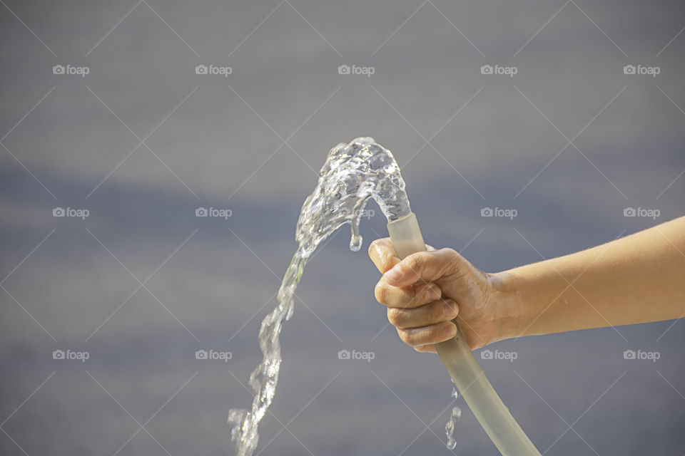 Hand boy holding the rubber tube and the water flows out