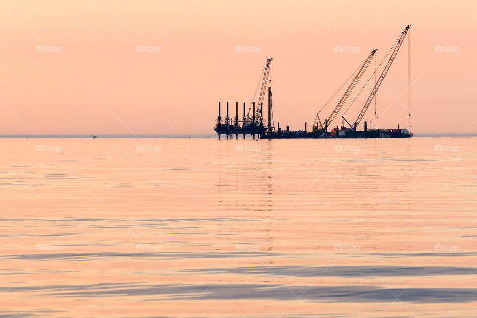 Black silhouette of barge on a pink sunsire water background