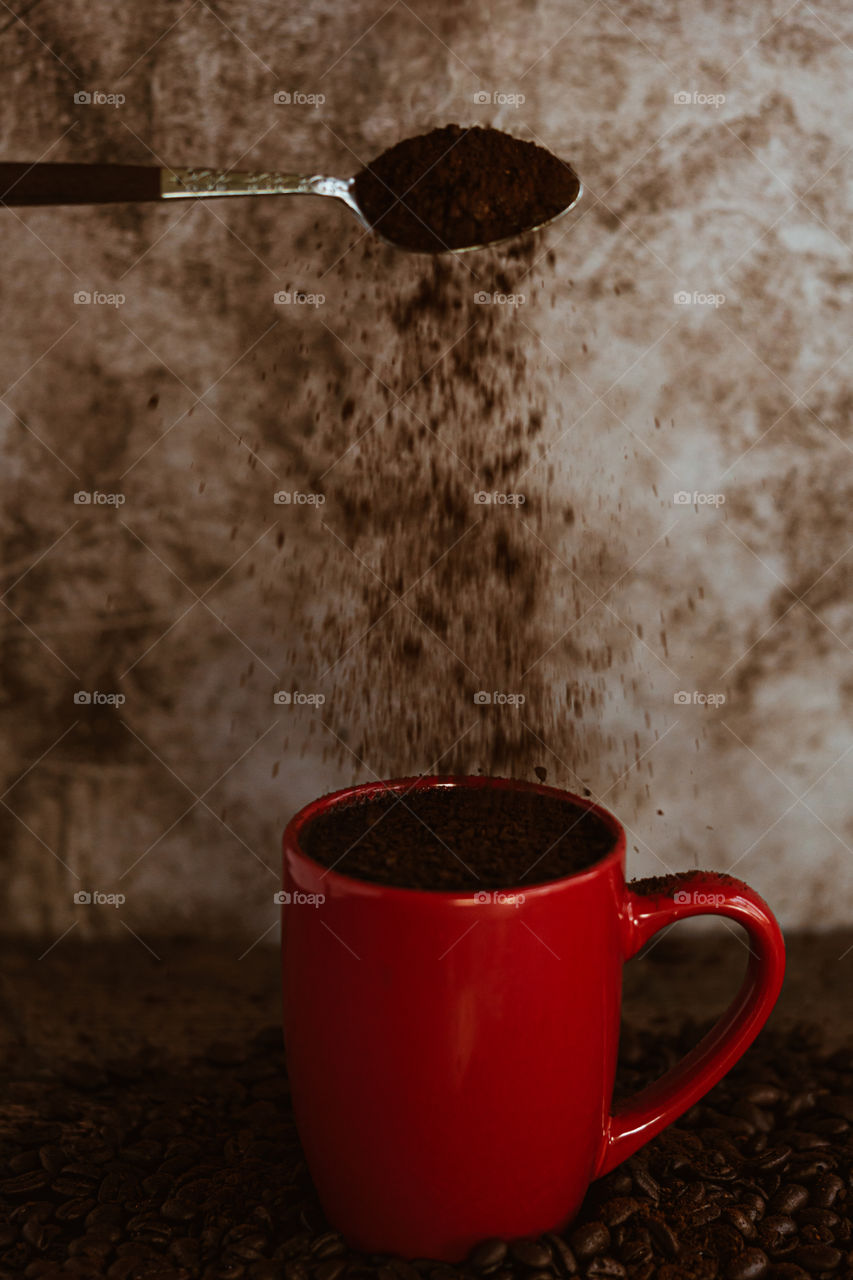 Red coffee mug with coffee grind pouring over