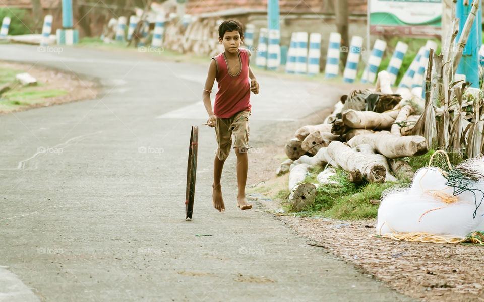A boy running with a Cycle Tyre