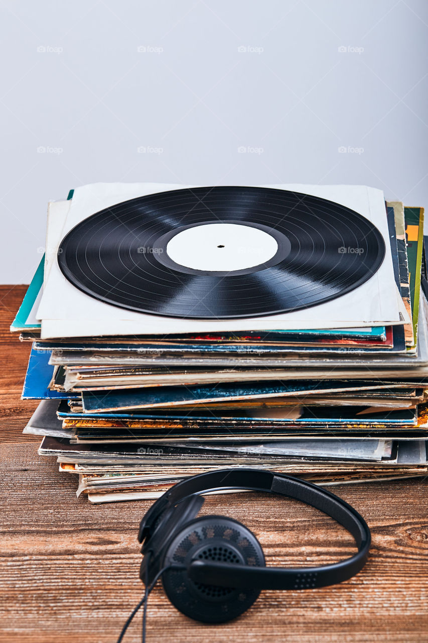 Stack of many black vinyl records, headphones put on the stack. Classic stereo set. Candid people, real moments, authentic situations