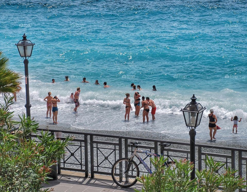 Fun in the sun. Swimmers play in the aqua blue ocean in Italy 