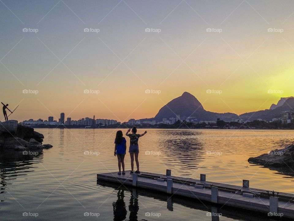 Two girls by a lake,with a beautiful sunset