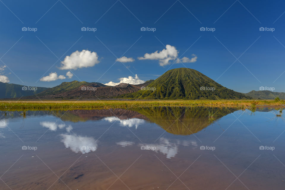 reflection of Mount Bromo from a pool of water