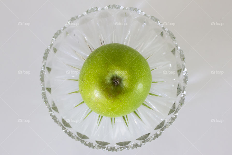 Green apple on crystal plate , from above 